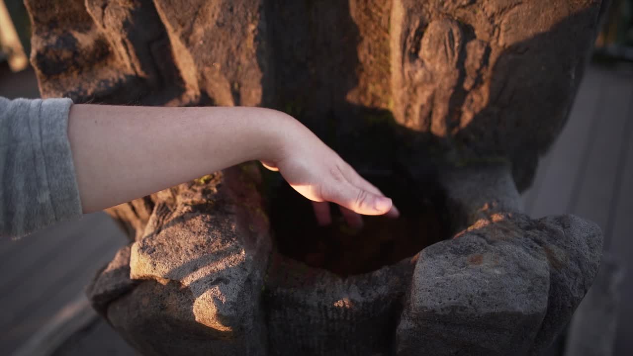 Hand touching water in a stone basin