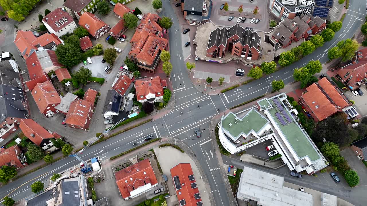 Car turning on junction of small German town with historic buildings and red brick houses. Aerial top down shot