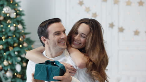 Cheerful-man-getting-new-year-gift-in-luxury-house.-Smiling-woman-hugging-man