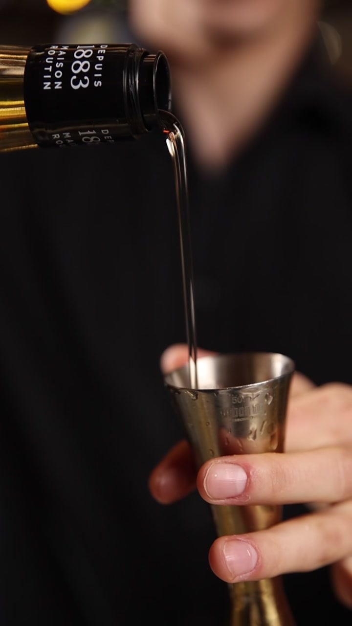 Primo piano di un barman che versa sciroppo nel jigger per un cocktail