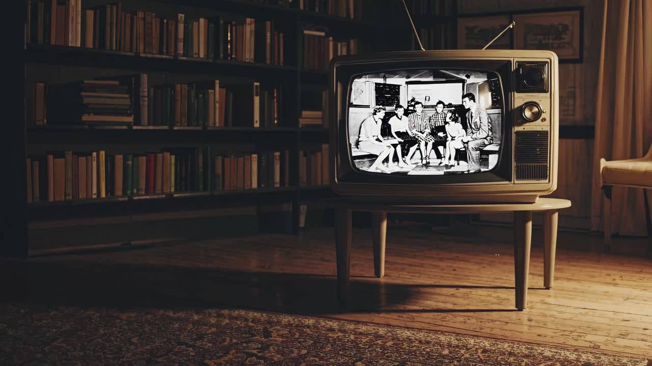 Vintage TV on a wooden table in a dimly lit room, showing a black-and-white video
