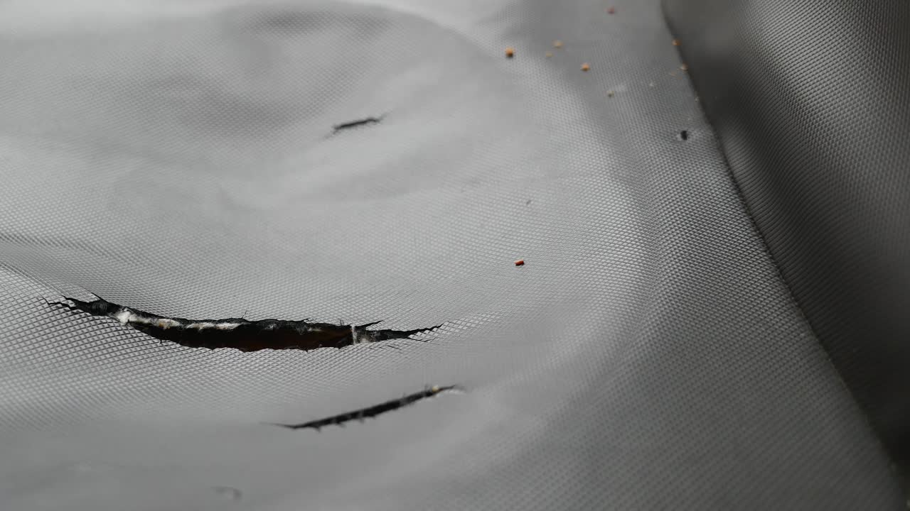 Close-up of torn grey mesh fabric