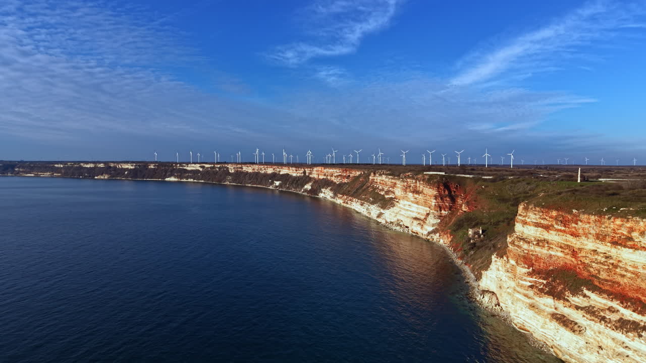 Vista panoramica della costa con scogliere e turbine eoliche vicino all'acqua durante le ore diurne