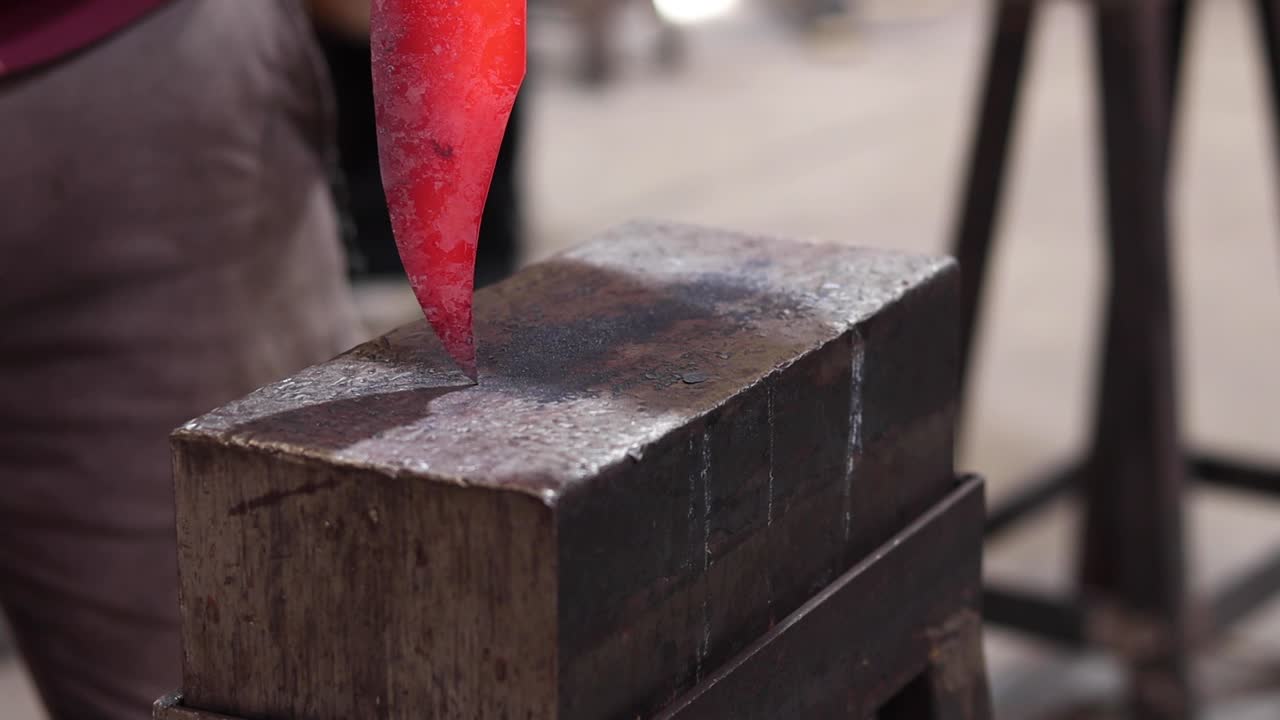 Blacksmiths forging hot metal with hammer in workshop
