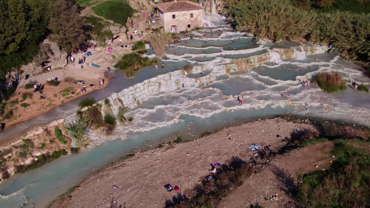 Turistas se bañan en humeantes aguas termales al amanecer en Terme di Saturnia