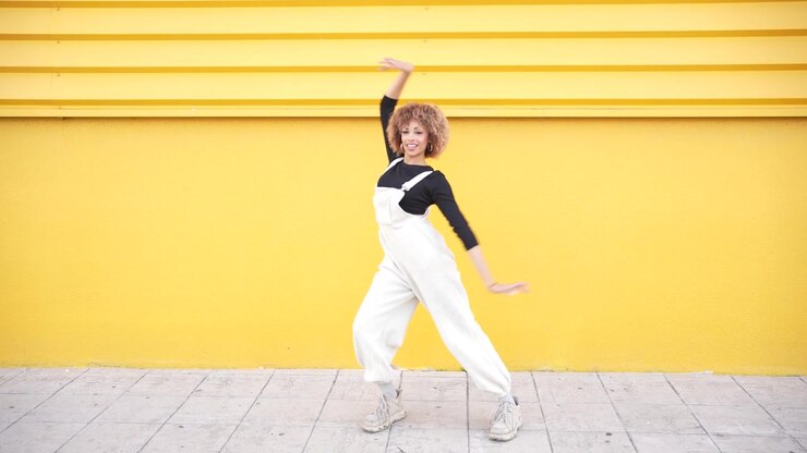 A stylish young woman posing confidently against a bright yellow wall radiating attitude