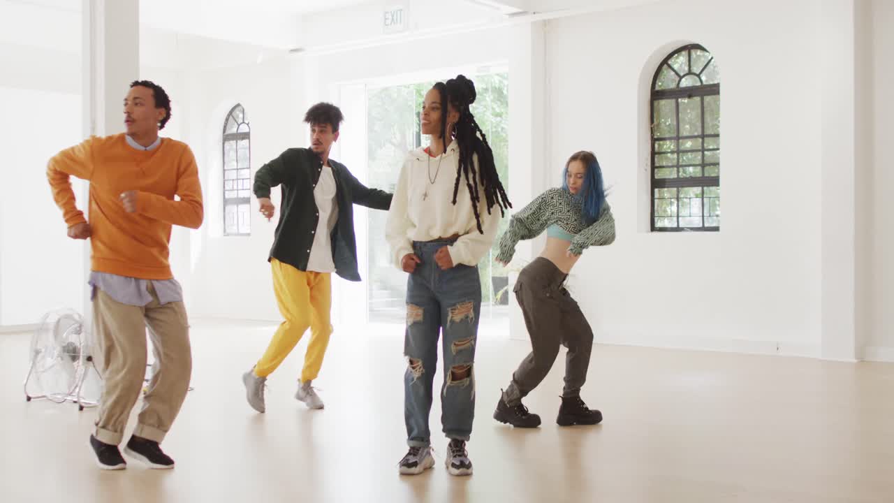 Happy diverse male and female dancers dancing in dance studio, slow motion