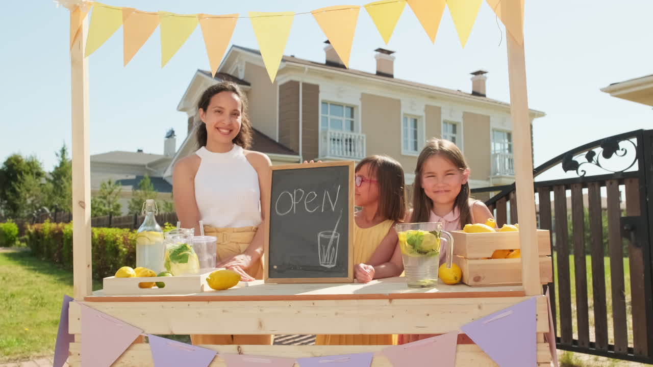 Mom And Daughters Selling Lemonade At Market