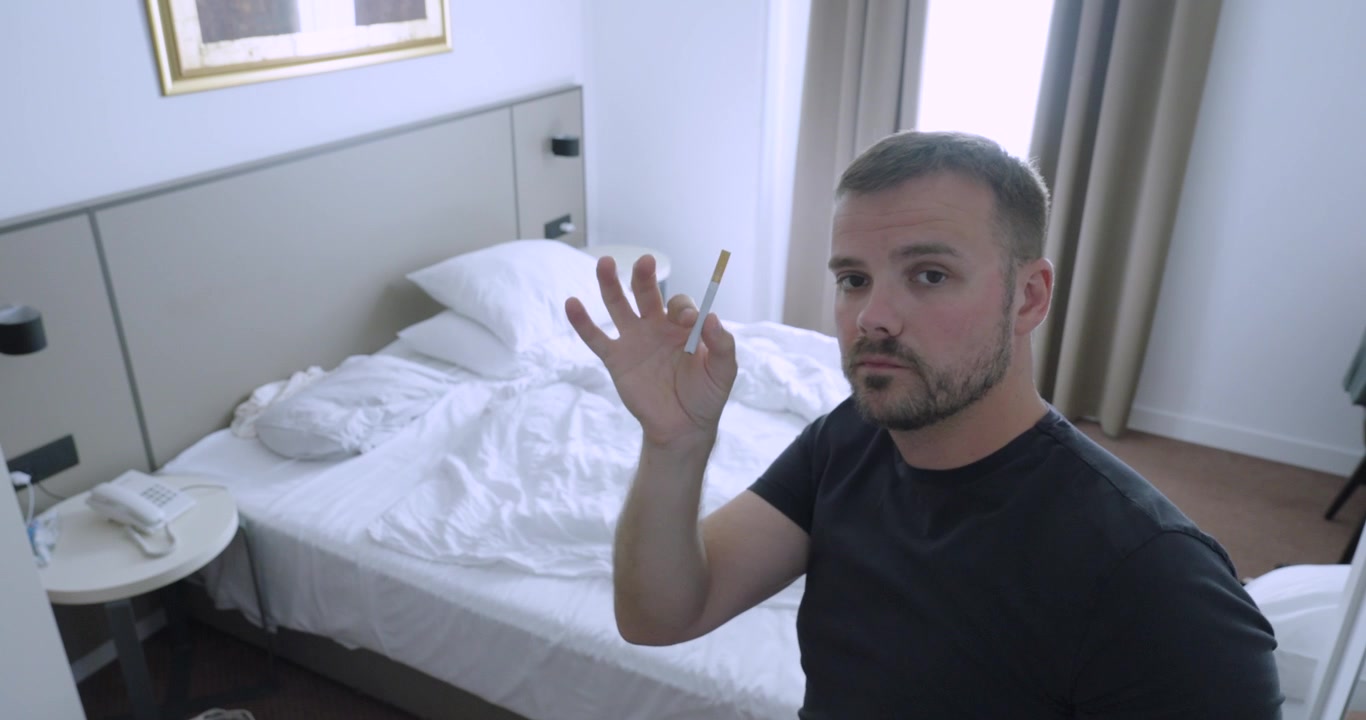 Mand på vej til at tænde en cigaret på et hotelværelse, før det angives, at rygning er forbudt. Rejsekoncept: hotelregler, røgfri politikker og gæsternes overholdelse