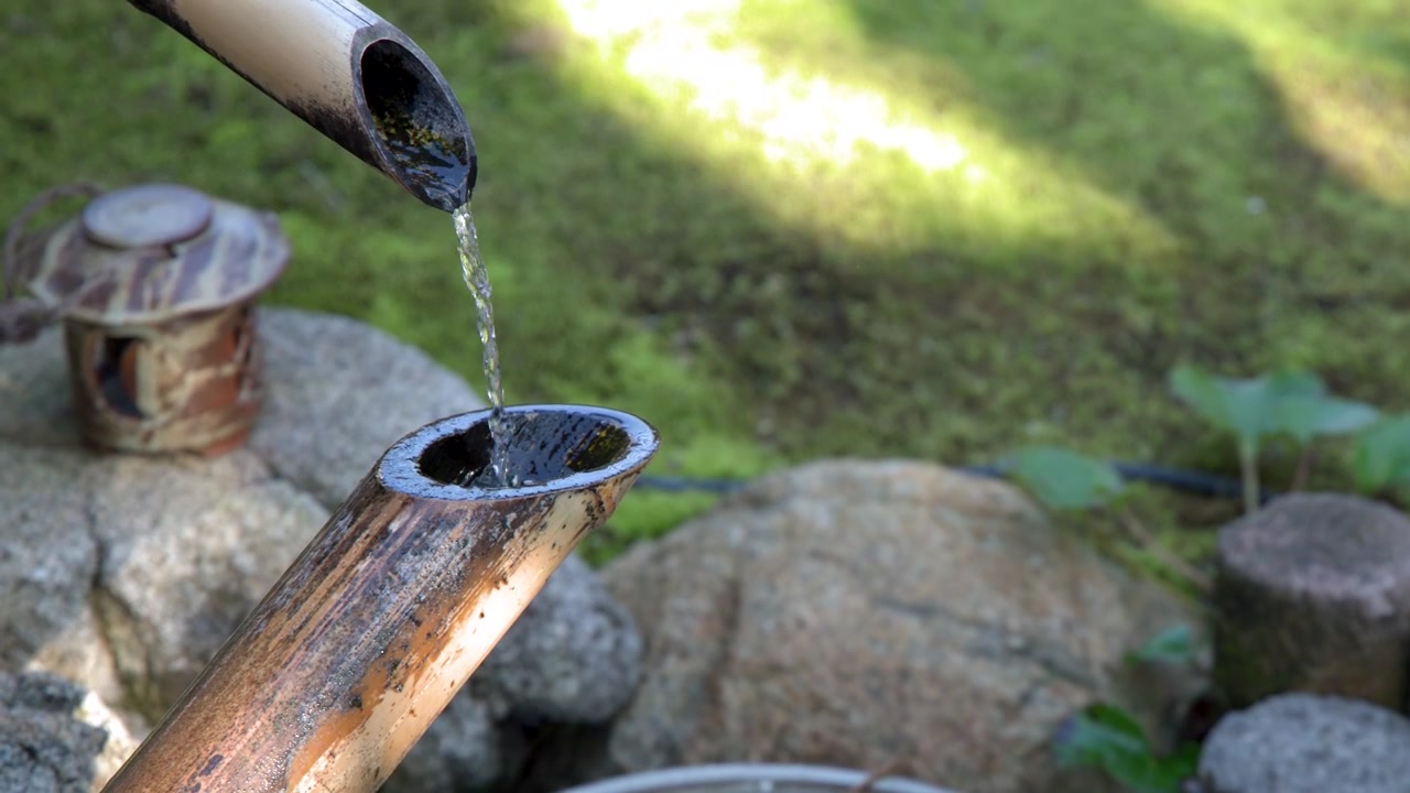 Primo piano di acqua che scorre attraverso tubi di bambù in una vasca di pietra a Kanazawa