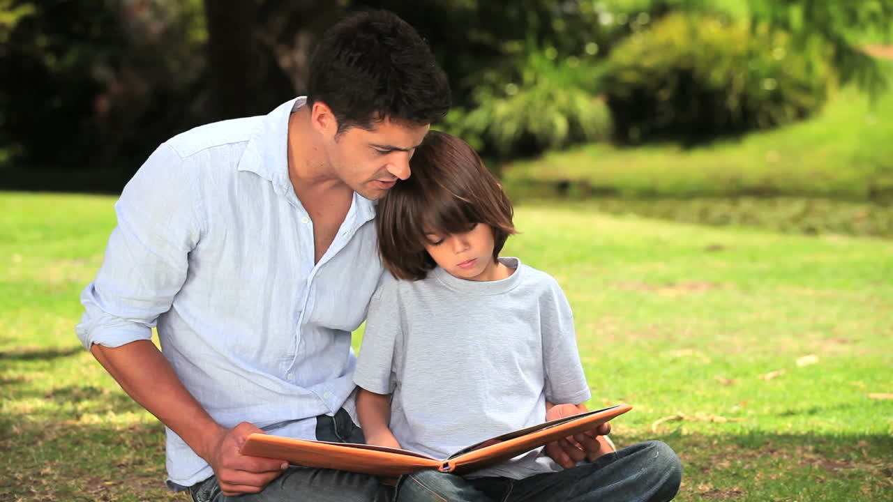 padre e hijo sentados leyendo al aire libre