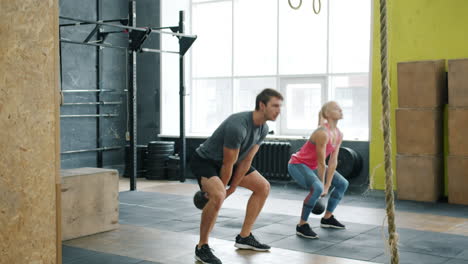 couple working out with kettlebells in gym