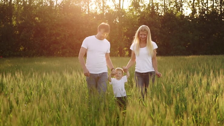 famiglia felice, mamma papà e figlio in una passeggiata emotiva. correre e godersi la vita in un campo verde all'aria fresca, cielo blu, natura