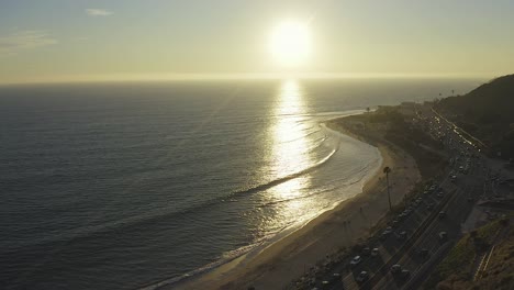 cinematic aerial view of traffic on california state route one at sunset with pacific coastline and surrounding nature