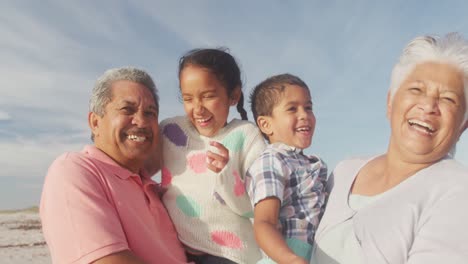 Glückliche-Hispanische-Großeltern-Und-Enkelkinder,-Die-Sich-Bei-Sonnenuntergang-Am-Strand-Vergnügen
