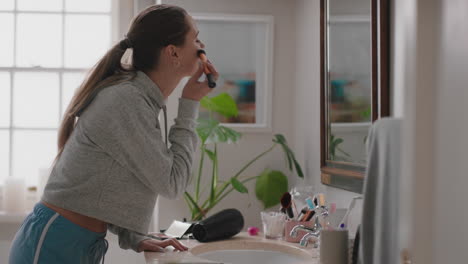 beautiful teenage girl looking in mirror getting ready applying makeup in bathroom