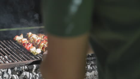 cocinar al aire libre barbacoa como cocinero voltea pinchos de pollo en la parrilla caliente