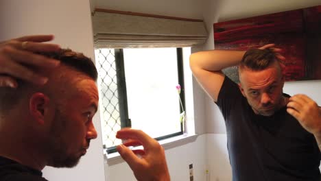 hombre peinando su cabello por la mañana usando pomada y sus manos para obtener una mirada de espalda lisa, en cámara lenta