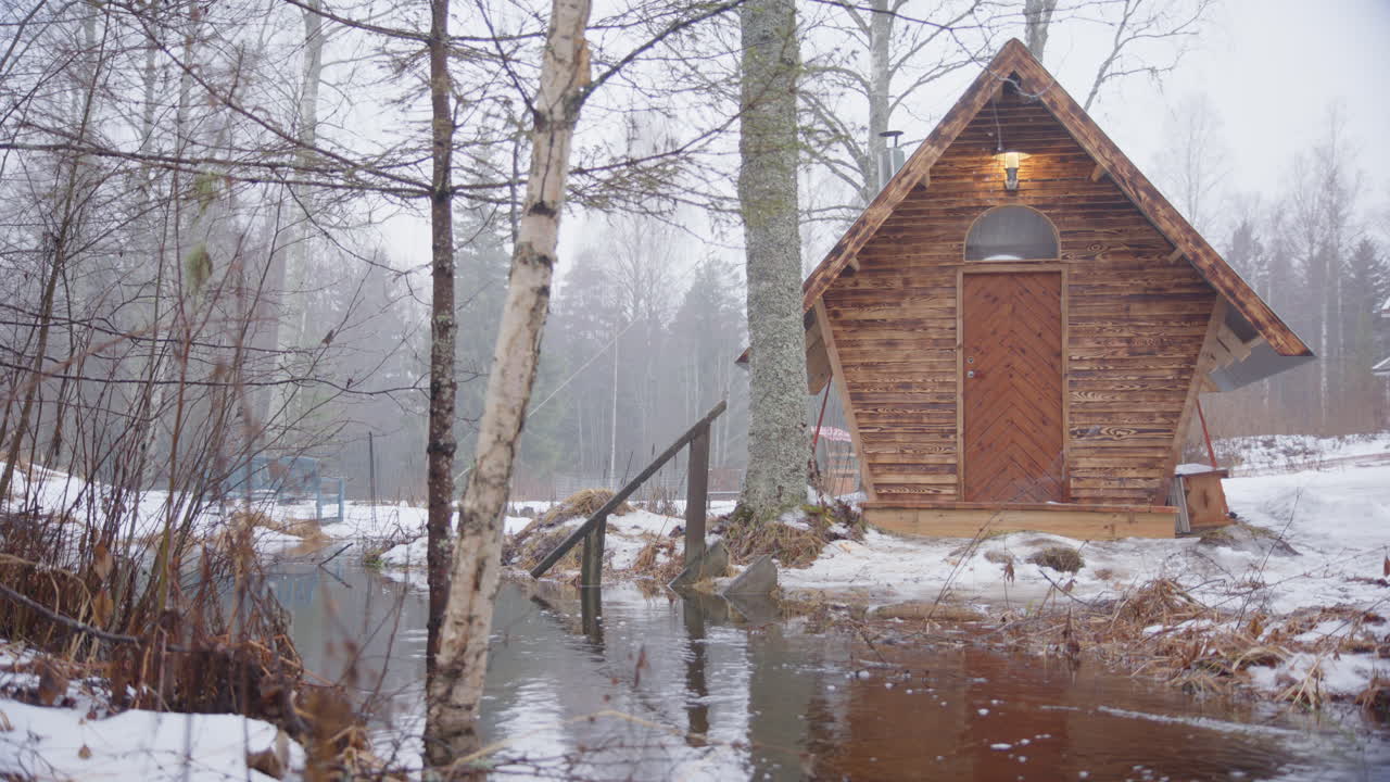 Rising river level causing flooding around tiny house in snowy winter woodland