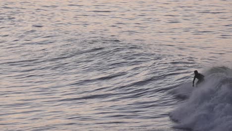 surfer does a nice wipe out while riding golden waves at sunset with water splashing over his head