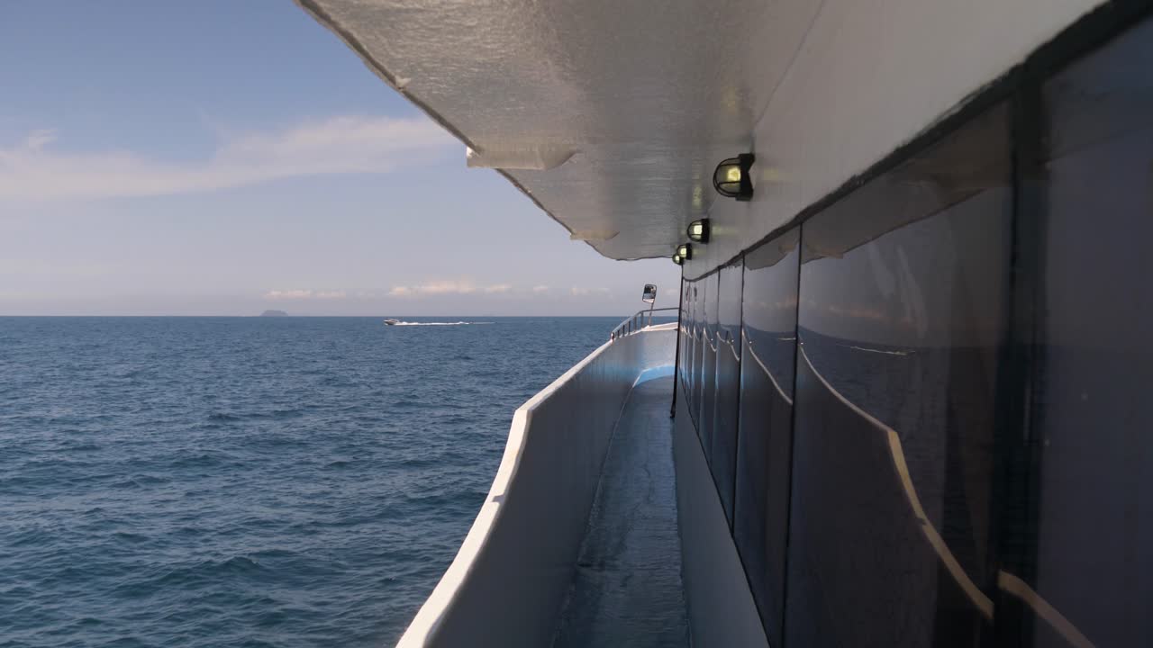 A ferry boat cutting through the blue waters of the Andaman Sea with a clear sky above