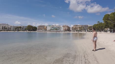 sunny beach with resort buildings and people by the calm bay