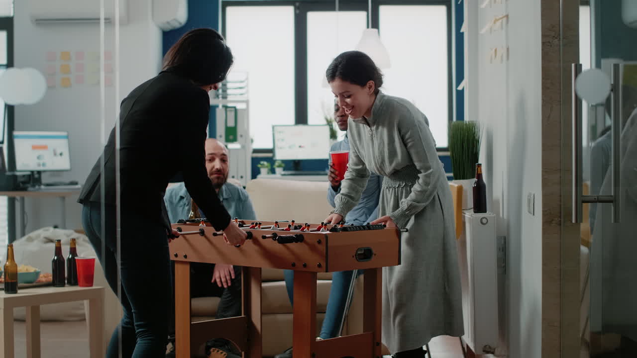 Happy women playing game at foosball table after work