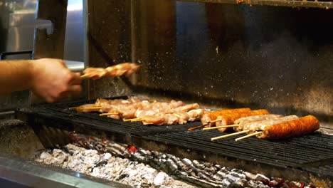 The-chef-prepares-sausages,-skewered-meat,-and-garlic-croutons-on-the-grill