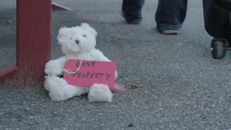 teddy left on train platform as commuter goes by with suitcase close up low shot