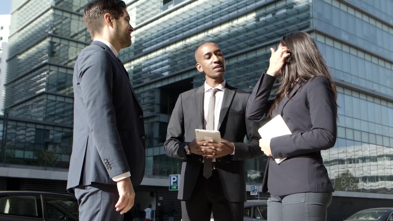 Coworkers with digital devices talking on street