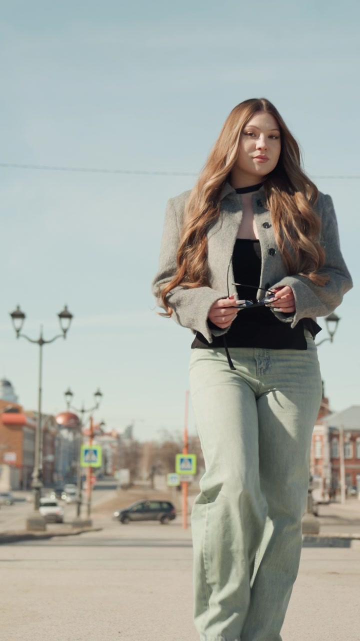 Donna alla moda a passeggio in città. Signora chic che passeggia con disinvoltura accanto all'architettura storica. Donna elegante con occhiali da sole che vaga con nonchalance per il centro storico con illuminazione calda e inquadratura artistica.