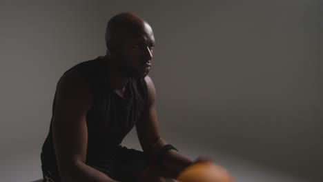 Studio-Shot-Of-Seated-Male-Basketball-Player-With-Hands-Holding-Ball-3