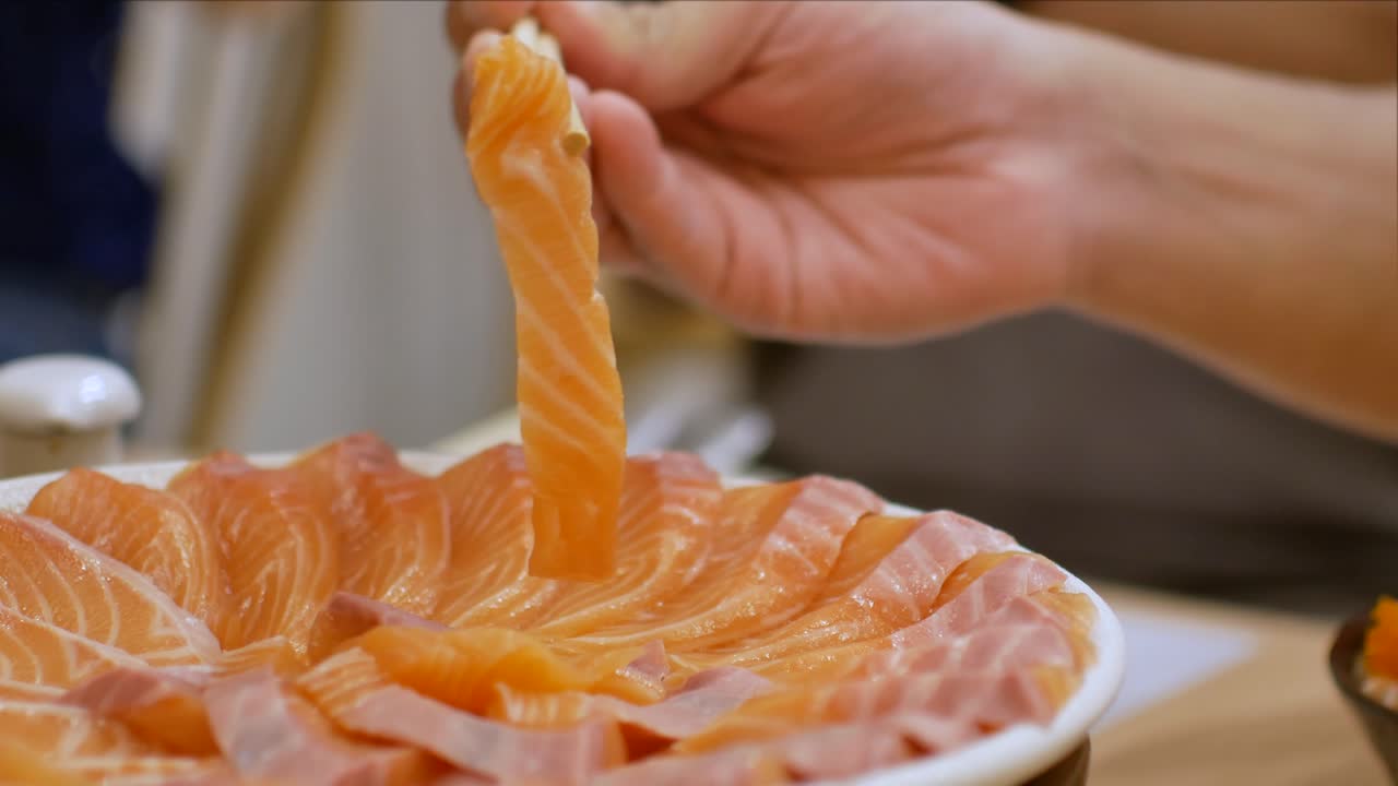 video de 4k del uso de chopctick pick slamon de un plato lleno de sashimi de salmón, comida de estilo japonés de pescado crudo