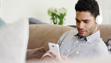 happy man listening music on mobile phone in living room