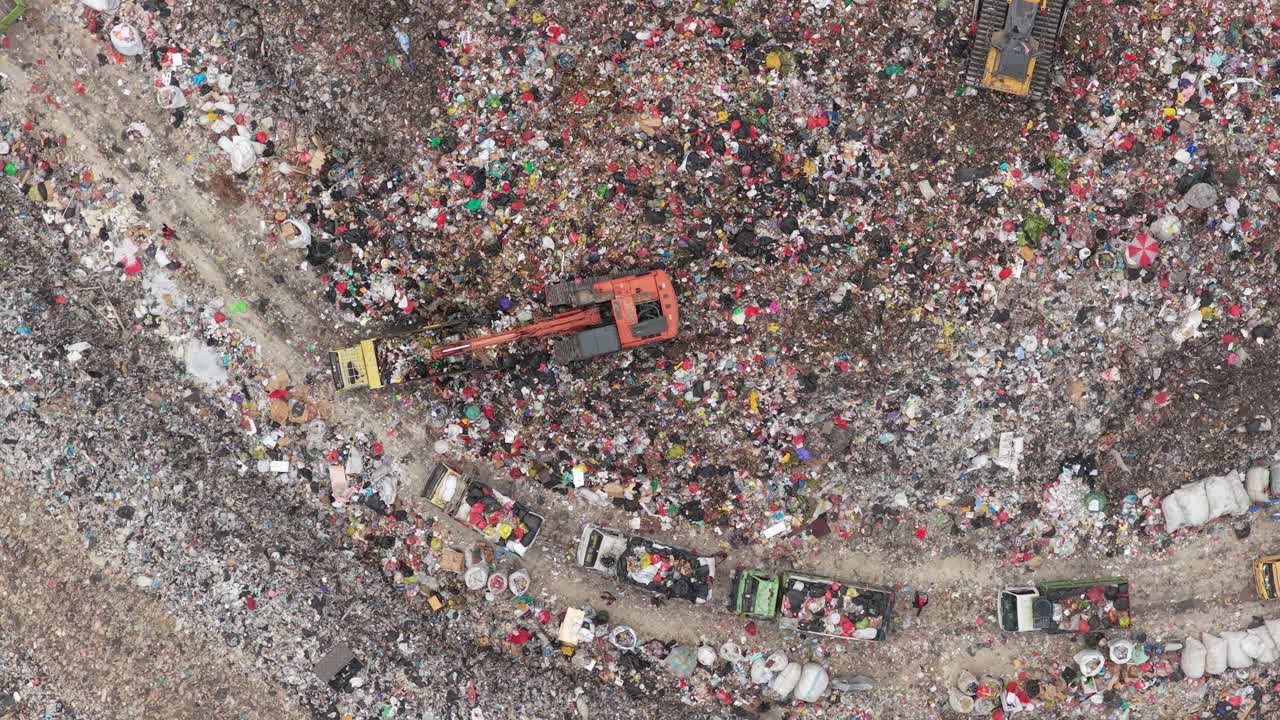 Bulldozer ed escavatore operanti in una massiccia discarica di rifiuti