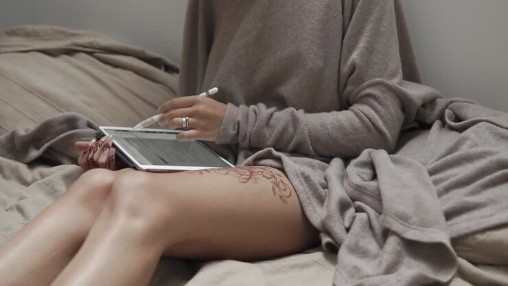 Frau, die Tablette auf Bett verwendet