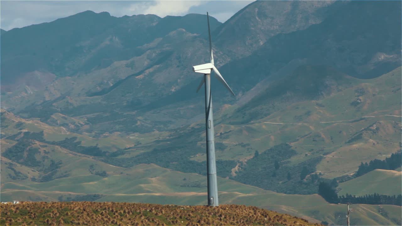 molino de viento girando con montañas en el fondo, turbina eólica de energía eólica generando electricidad, futuro de energía verde - disparo estable