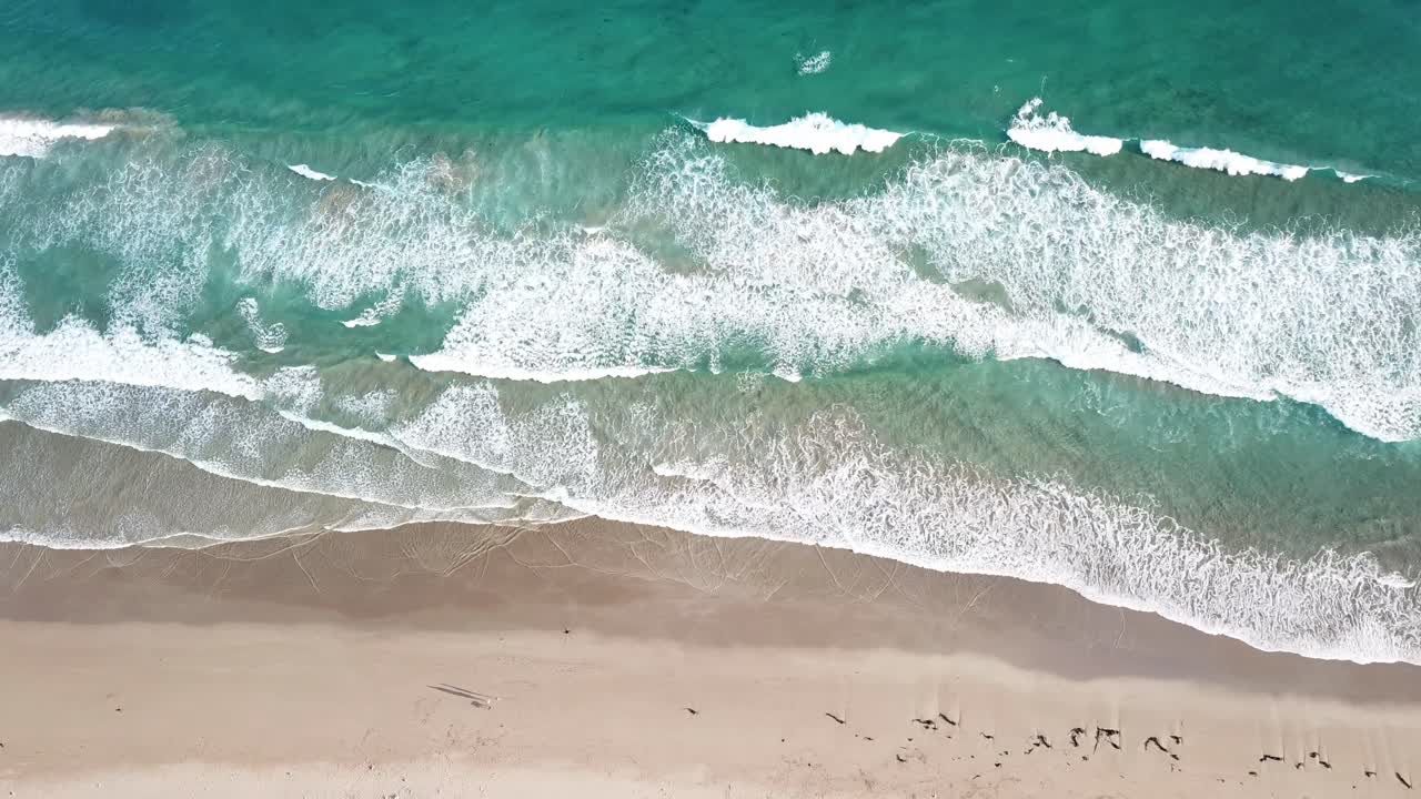 Drone arial over blue beach with waves and sandy bay moving sideways birds eye view