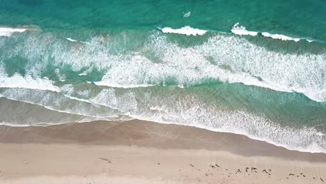 drone arial over blue beach with waves and sandy bay moving sideways birds eye view