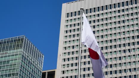 Bandera-De-Japón-Con-Fondo-De-Edificio-Moderno-De-Gran-Altura-En-Tokio,-Japón