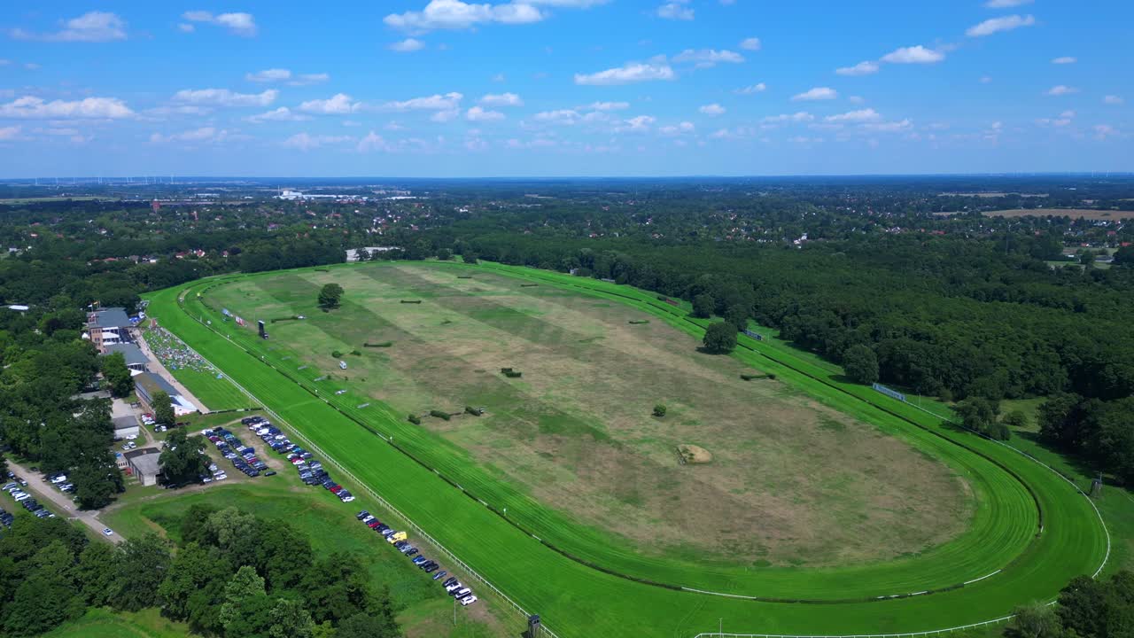 Horse gallop racecourse near a forest in Germany, parking lot visible. Unique aerial view flight ascending drone