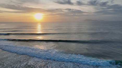 Drone-clip-of-surfers-riding-perfect-waves-at-golden-sunset-at-a-world-class-surf-break-on-the-island-of-Java,-Indonesia