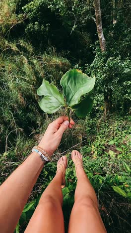 woman holding a large leaf in a lush forest