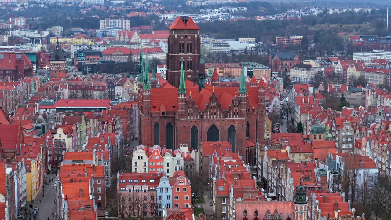 Largest ancient brick gothic St Marys Church in old town of Gdansk surrounded with beautiful red brick terraced houses and mansions, Europe, Establishing shot, Drone