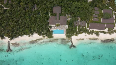 Top-view-of-a-hotel-with-a-jetty-in-the-Maldives-island-with-many-green-plants-and-breakwaters