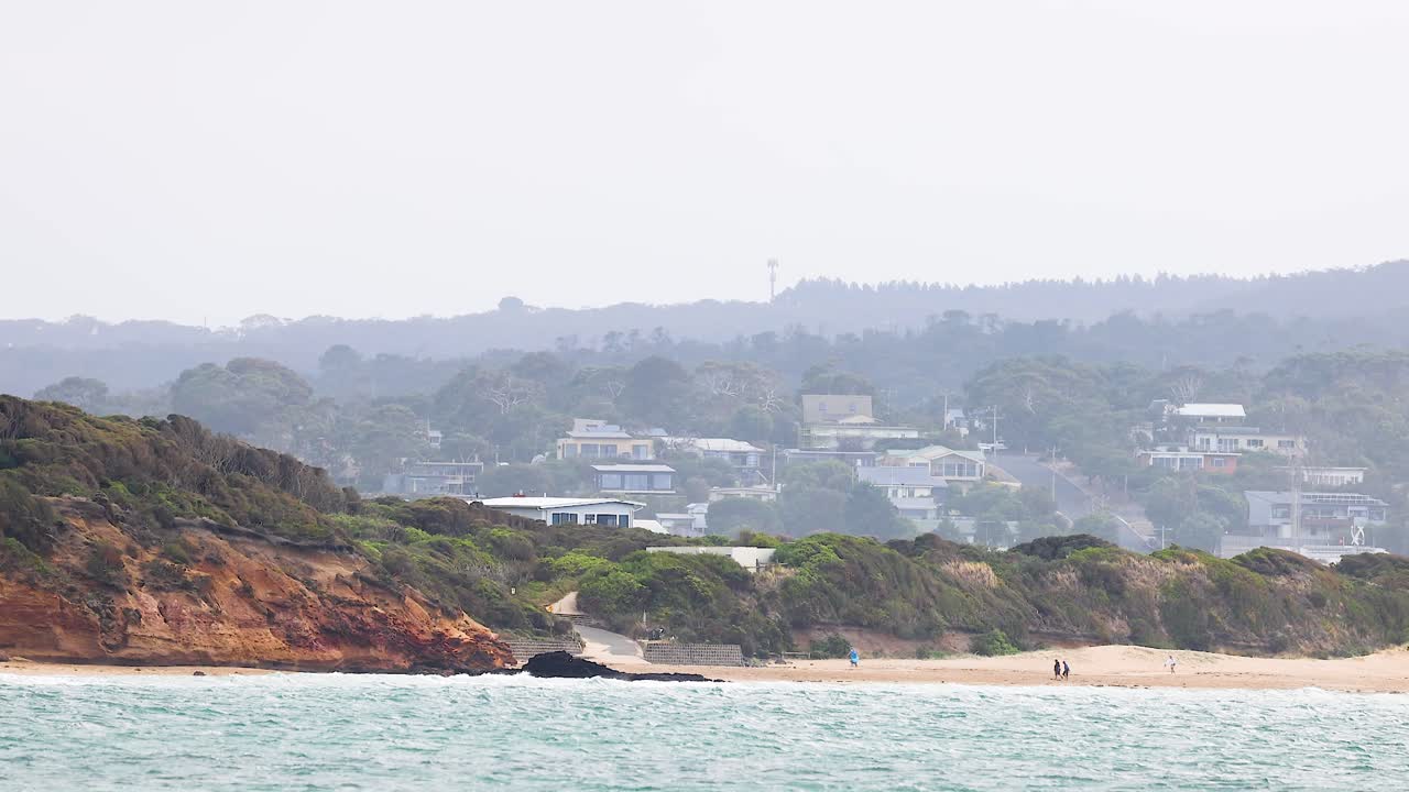 A tranquil coastal scene with gentle waves and distant hills under soft daylight, captured at Great Ocean Road, Australia