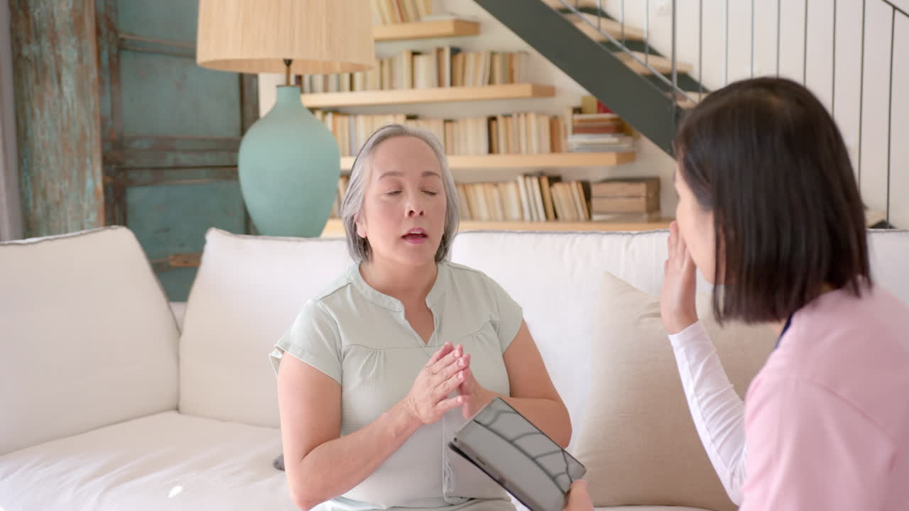 Senior asian woman in home therapy session, communicating with therapist holding tablet
