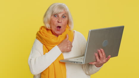 excited happy senior woman working on laptop winning lottery game celebrating success victory