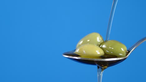 The olives are in a spoon of olive oil flows.