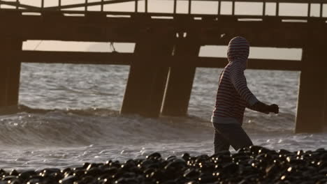 child walking on the beach at sunset near a pier